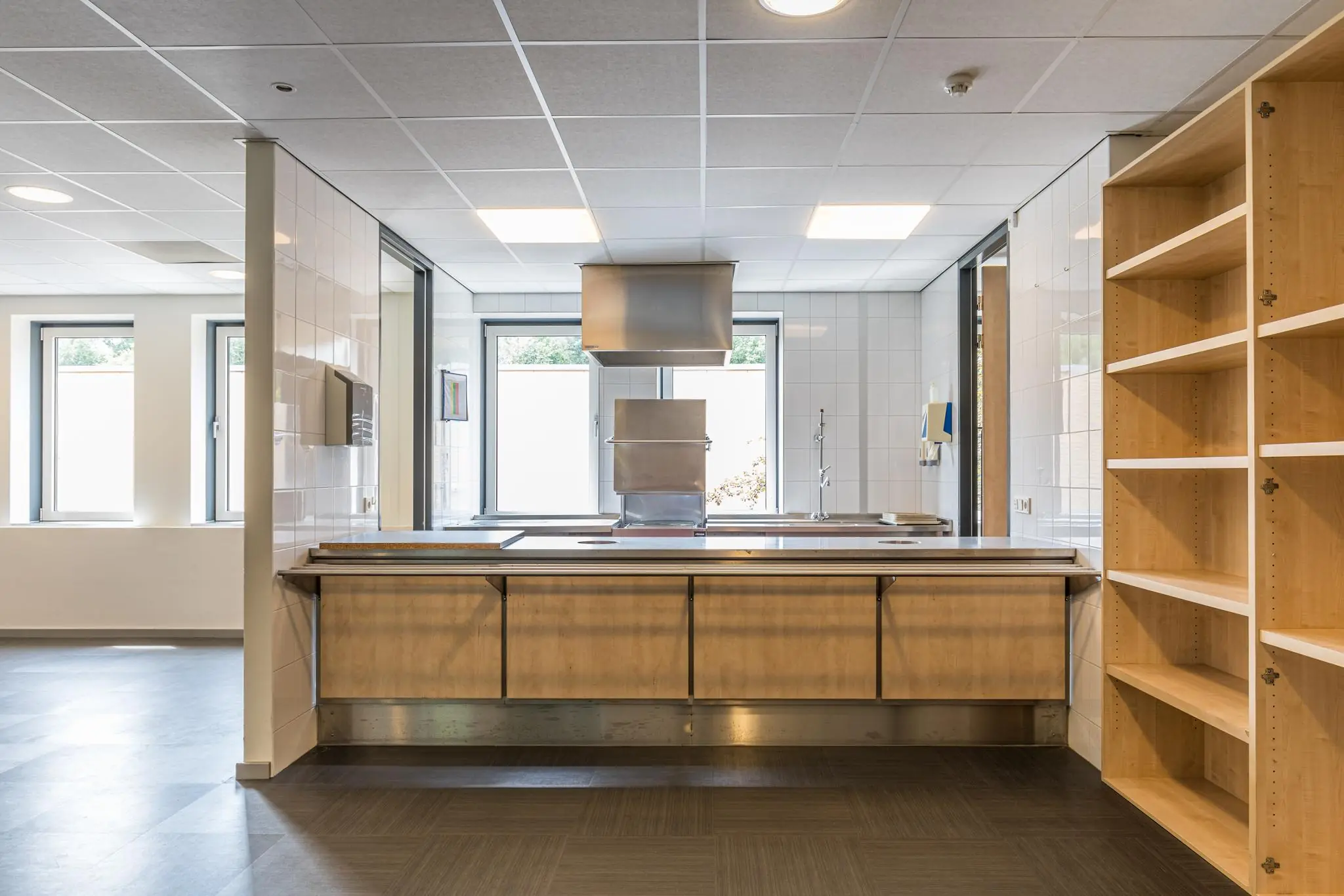 Moderne, lichte keukenruimte met houten kasten, een centraal kookeiland en roestvrijstalen afzuigkap in Laan Blussé van Oud-Alblas.